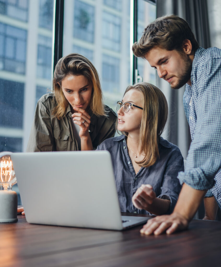 Group of young colleagues using laptop. People working or studying together. Business team in office. Teamwork. Startup concept